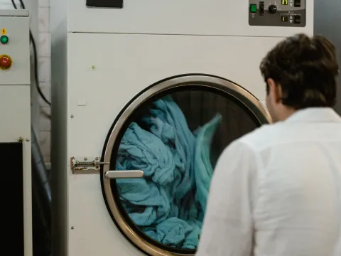 Pumice stones and denim garments inside an industrial drum mid dry-tumble cycle