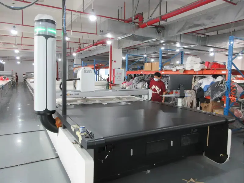 Fabric cutting room with automated spreader machine