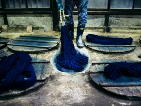 Bundled cotton warp yarn being dipped into an indigo dye vat during rope dyeing