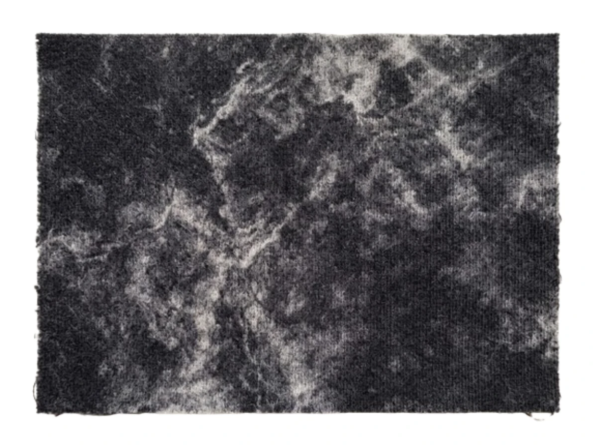 Washed-black fleece swatch with pronounced high-contrast acid wash marbling