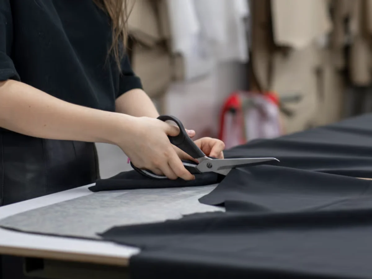 Worker trimming loose threads and inspecting a finished embroidered logo