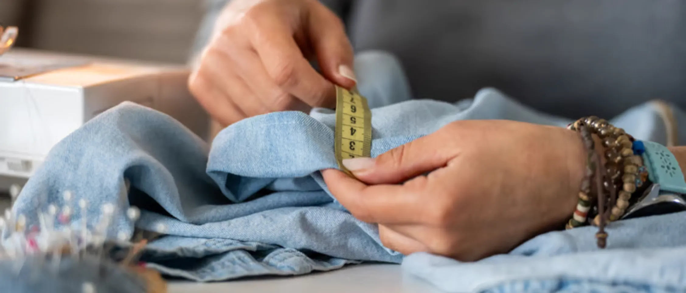 Measuring a hoodie sample across the chest beside its specification chart